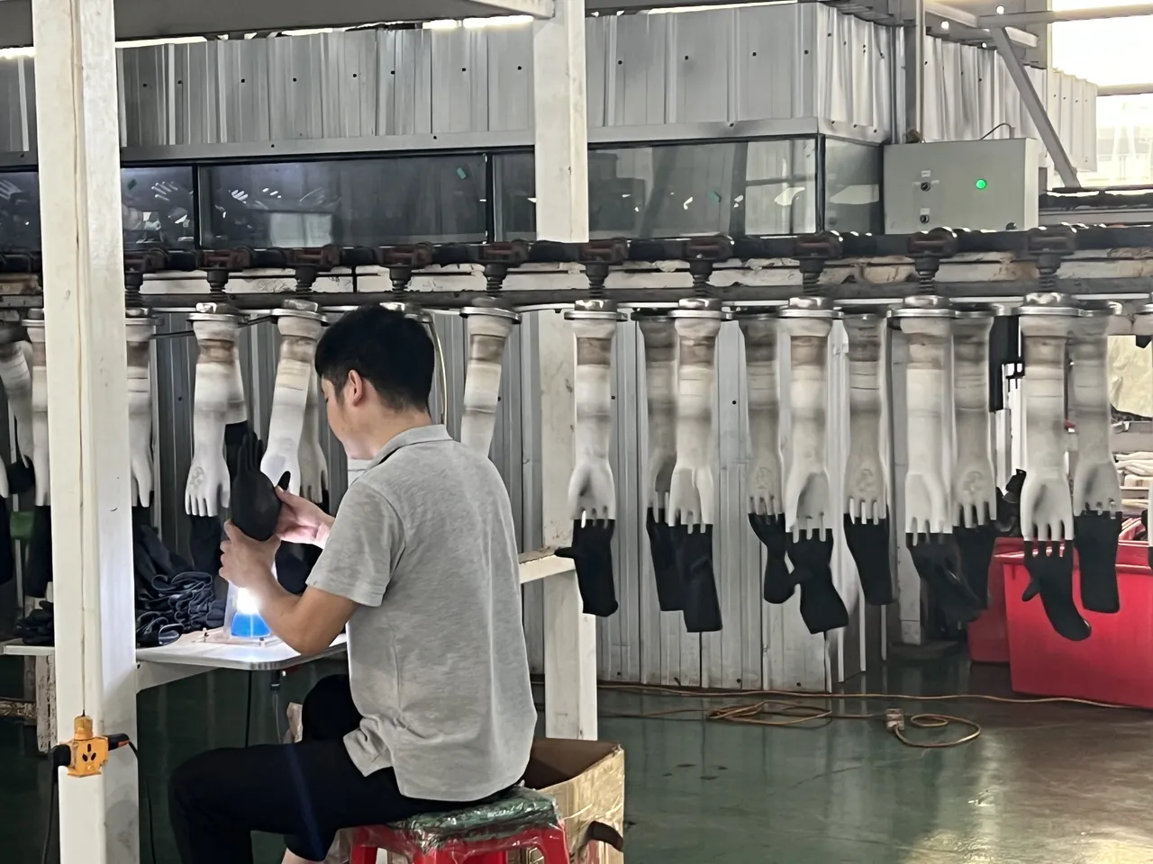 Worker inspecting black gloves on the production line