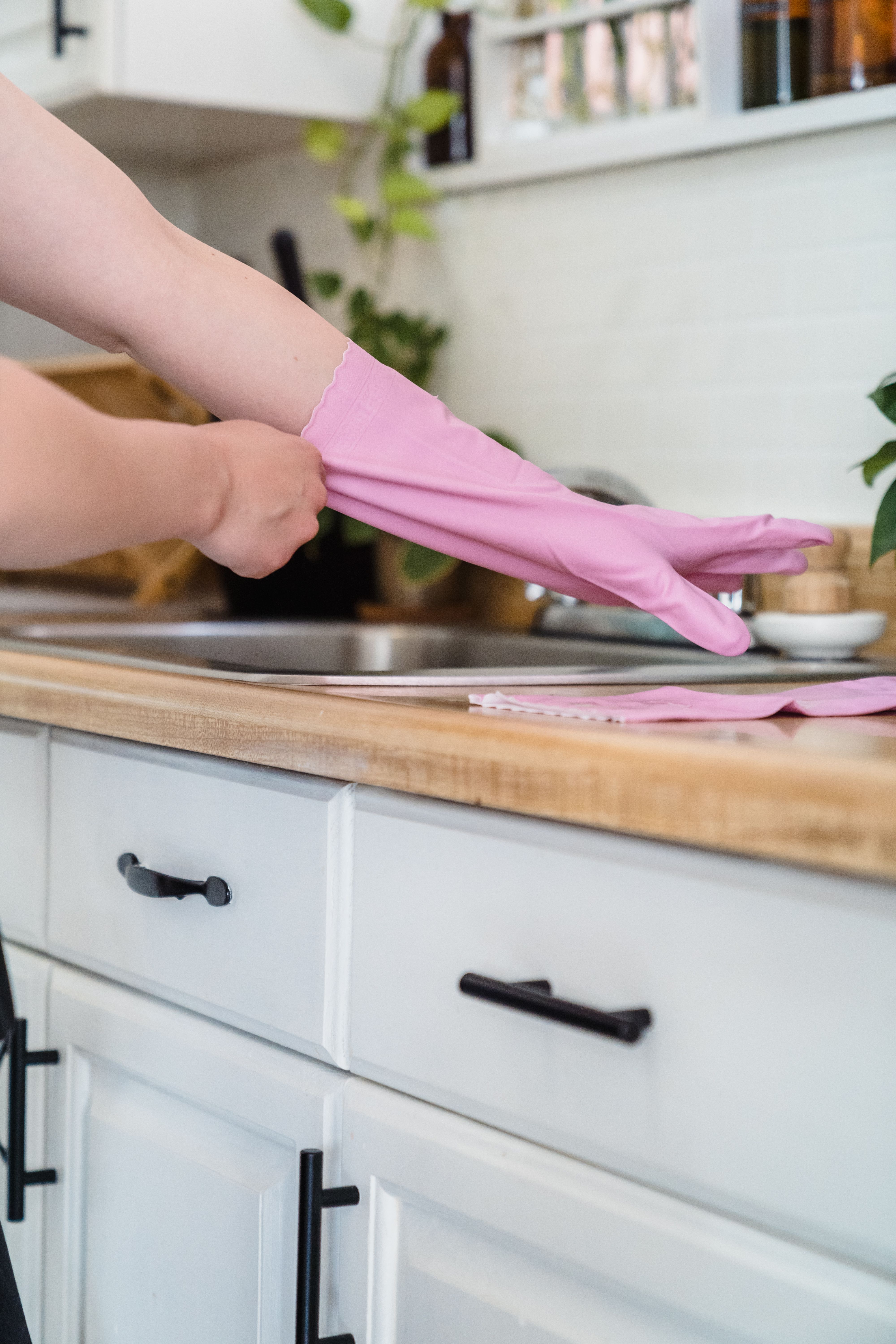 Pink rubber glove being put on in a home kitchen