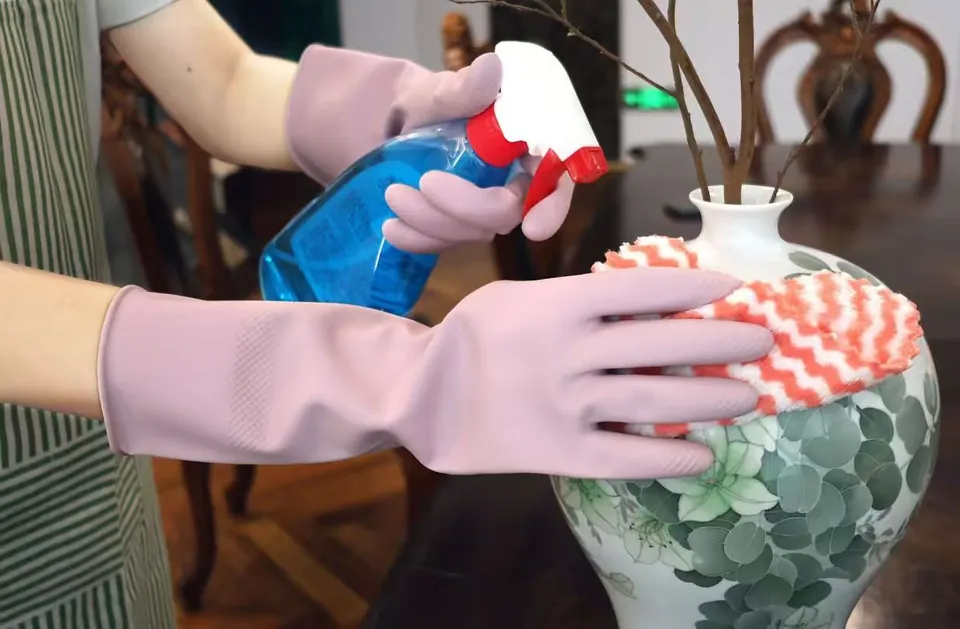 Lavender latex gloves cleaning a vase with a spray bottle